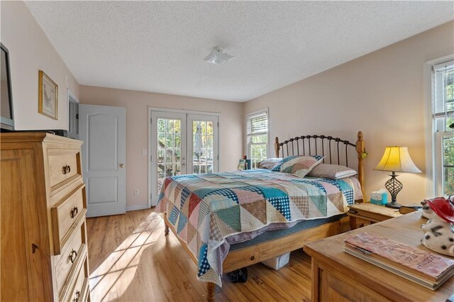 bedroom featuring access to outside, multiple windows, a textured ceiling, and light wood-type flooring