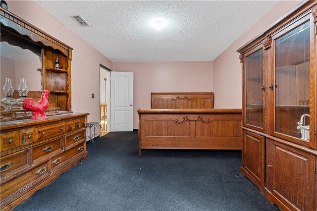 bedroom with dark carpet and a textured ceiling