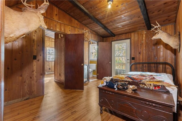 bedroom with light wood-type flooring, wooden ceiling, vaulted ceiling with beams, and wooden walls