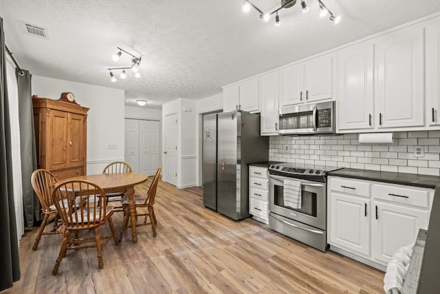 kitchen with white cabinetry, light wood-type flooring, a textured ceiling, and appliances with stainless steel finishes