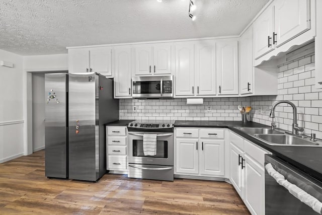 kitchen featuring white cabinetry, sink, stainless steel appliances, dark hardwood / wood-style flooring, and backsplash