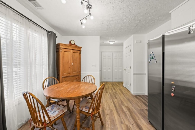 dining room with a textured ceiling and light hardwood / wood-style floors