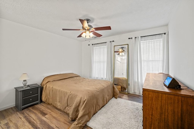 bedroom with ceiling fan, light wood-type flooring, and multiple windows