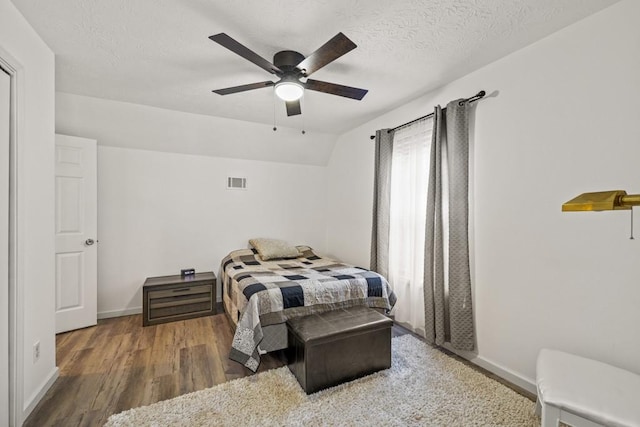 bedroom featuring a textured ceiling, dark hardwood / wood-style floors, ceiling fan, and lofted ceiling