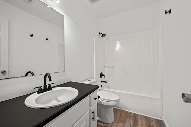 full bathroom featuring toilet, hardwood / wood-style floors, vanity, and bathing tub / shower combination