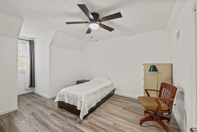 bedroom featuring ceiling fan, light hardwood / wood-style flooring, and a textured ceiling