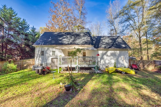 rear view of property featuring a wooden deck and a lawn