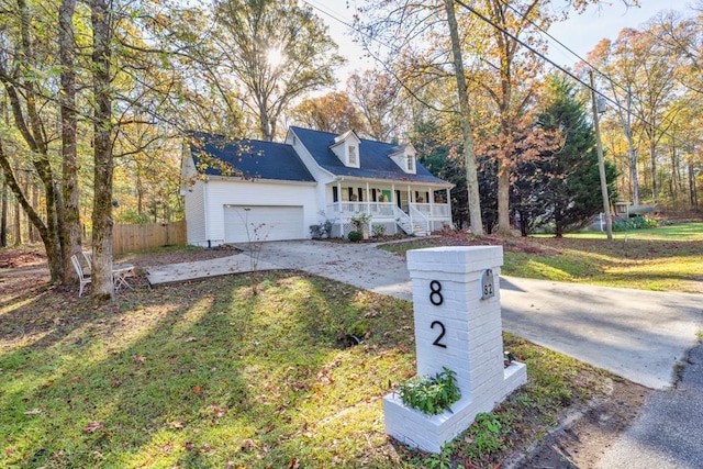 cape cod house featuring a porch, a garage, and a front lawn