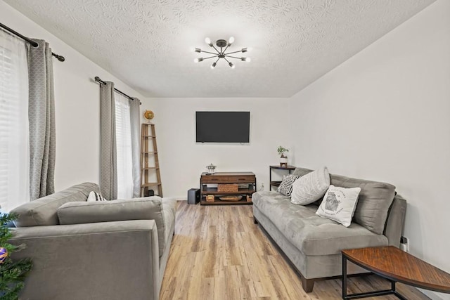 living room featuring a textured ceiling, an inviting chandelier, and light hardwood / wood-style flooring