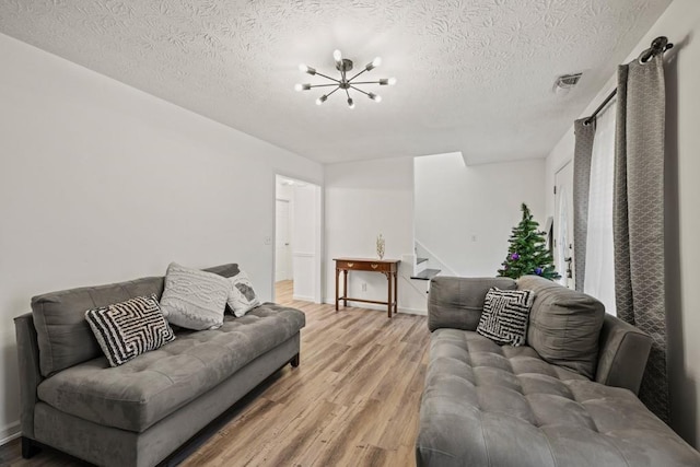 living room featuring a chandelier, wood-type flooring, and a textured ceiling