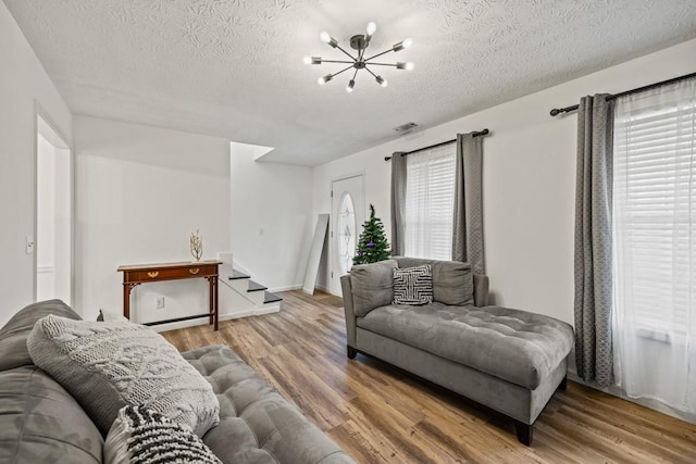 living room featuring wood-type flooring, a textured ceiling, an inviting chandelier, and a healthy amount of sunlight