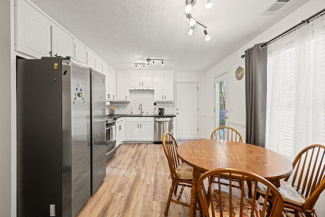 dining space with sink, light wood-type flooring, and a textured ceiling