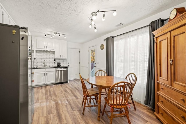 dining area with a textured ceiling, light hardwood / wood-style floors, and sink