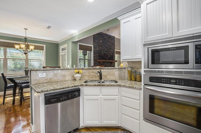 212 Westwind Dr, Newnan, GA 30263 - kitchen featuring stainless steel appliances, a peninsula, white cabinets, a chandelier, and crown molding