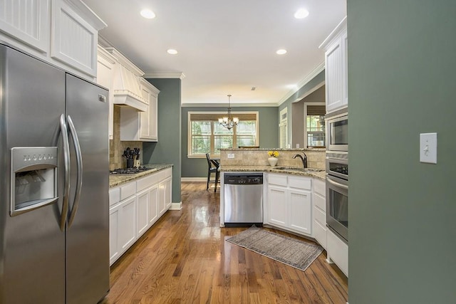 212 Westwind Dr, Newnan, GA 30263 - kitchen featuring stainless steel appliances, a peninsula, decorative backsplash, a chandelier, and ornamental molding