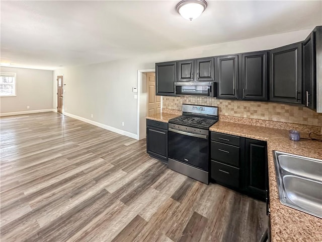 kitchen with tasteful backsplash, appliances with stainless steel finishes, sink, and light hardwood / wood-style flooring