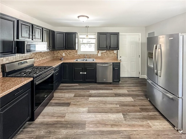 kitchen with tasteful backsplash, appliances with stainless steel finishes, sink, and light stone counters