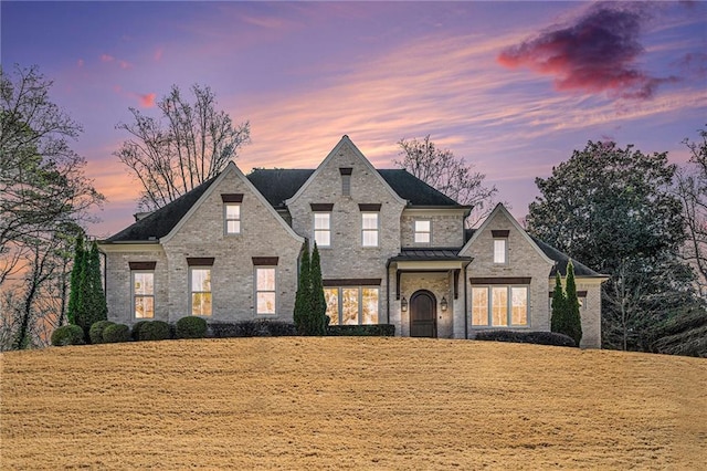 french country style house featuring brick siding