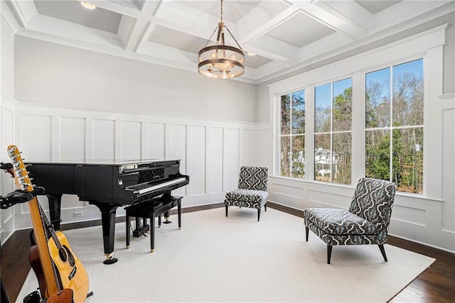 living area with a healthy amount of sunlight, a decorative wall, and beamed ceiling