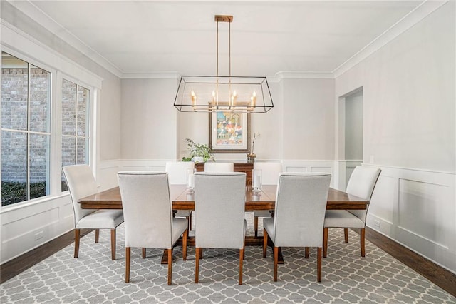 dining space featuring ornamental molding, wainscoting, wood finished floors, and a decorative wall