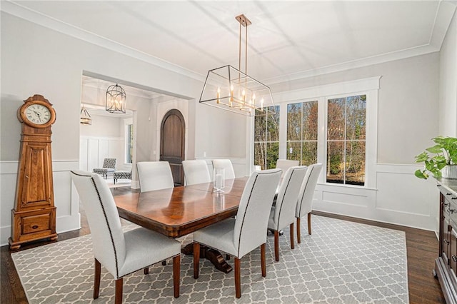 dining space featuring arched walkways, a wainscoted wall, ornamental molding, dark wood-type flooring, and a notable chandelier