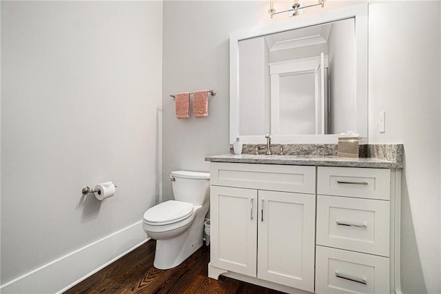 half bath featuring toilet, wood finished floors, and vanity