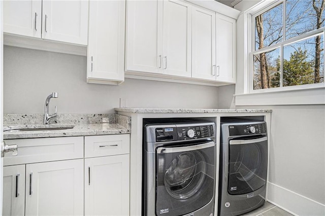 clothes washing area with baseboards, cabinet space, a sink, and washing machine and clothes dryer