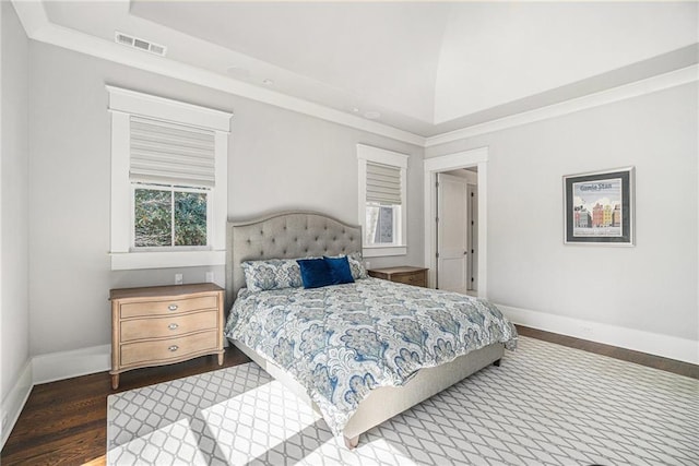 bedroom with lofted ceiling, wood finished floors, visible vents, and baseboards