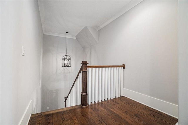 staircase featuring ornamental molding, a notable chandelier, baseboards, and wood finished floors