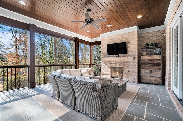 sunroom / solarium featuring an outdoor brick fireplace, wood ceiling, and ceiling fan