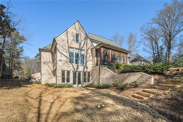 rear view of house featuring a sunroom, stucco siding, and a yard