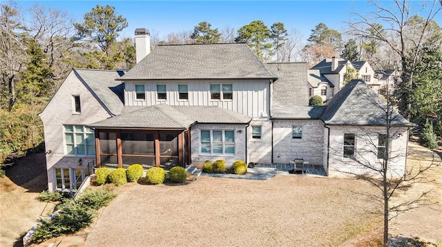 back of house featuring a chimney, board and batten siding, and a sunroom