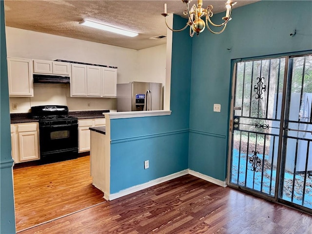 kitchen with black range with gas cooktop, a notable chandelier, under cabinet range hood, stainless steel fridge with ice dispenser, and white cabinets