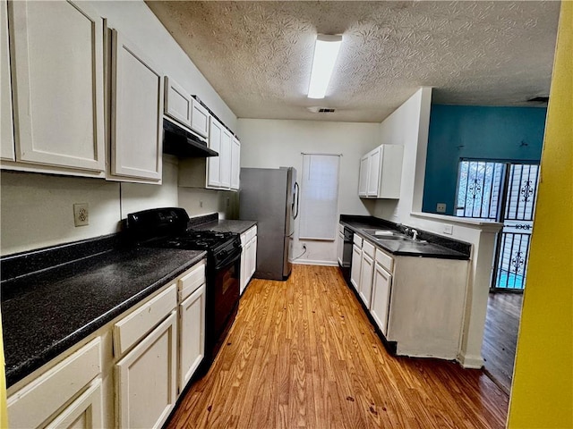 kitchen with under cabinet range hood, a peninsula, light wood-style flooring, and black appliances