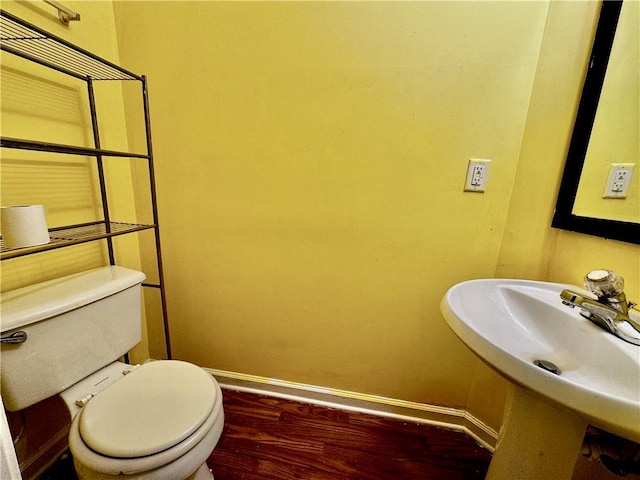 bathroom with baseboards, toilet, a sink, and wood finished floors