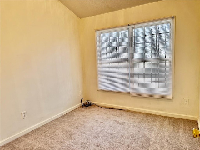 carpeted empty room featuring baseboards