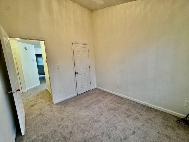spare room with baseboards, a high ceiling, and carpet