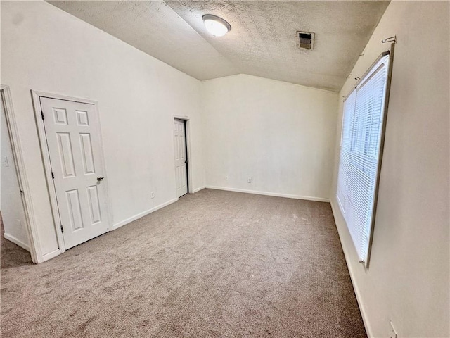 unfurnished bedroom featuring a textured ceiling, carpet, visible vents, vaulted ceiling, and baseboards