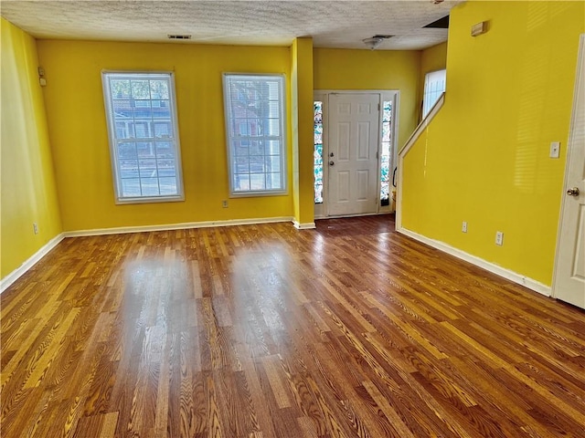 entryway with a textured ceiling, visible vents, wood finished floors, and baseboards