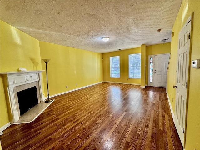 unfurnished living room with baseboards, a high end fireplace, a textured ceiling, and wood finished floors