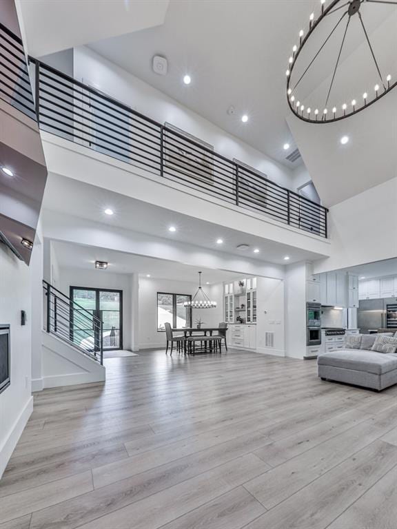 106 Belmont Dr, Canton, GA 30115 - living area featuring a chandelier, a high ceiling, light wood finished floors, a glass covered fireplace, and recessed lighting