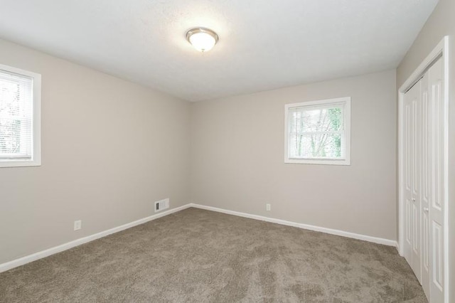 unfurnished bedroom featuring multiple windows, light colored carpet, and a closet