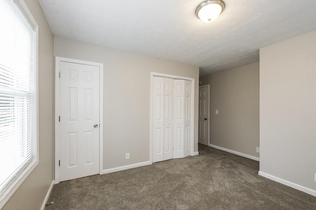 unfurnished bedroom featuring a closet and dark colored carpet