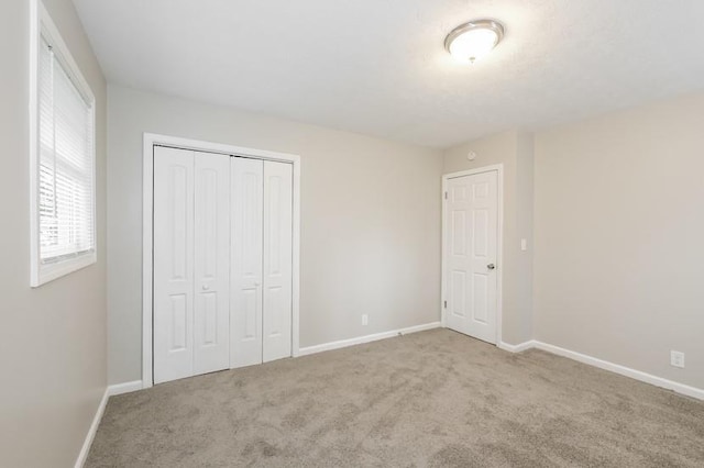 unfurnished bedroom with light colored carpet and a closet