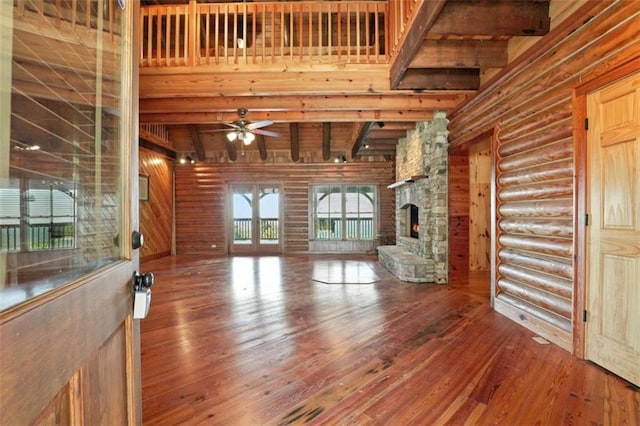 929 Hickory Nut Mountain Rd, Tallulah Falls, GA 30573 - unfurnished living room with log walls, hardwood / wood-style flooring, beam ceiling, a fireplace, and ceiling fan