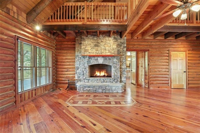 929 Hickory Nut Mountain Rd, Tallulah Falls, GA 30573 - unfurnished living room featuring wood-type flooring, a ceiling fan, a stone fireplace, log walls, and a wooden ceiling with exposed beams