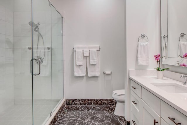 bathroom featuring vanity, marble finish floor, a stall shower, and toilet