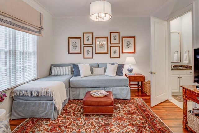 living area featuring ornamental molding, wood finished floors, and a notable chandelier