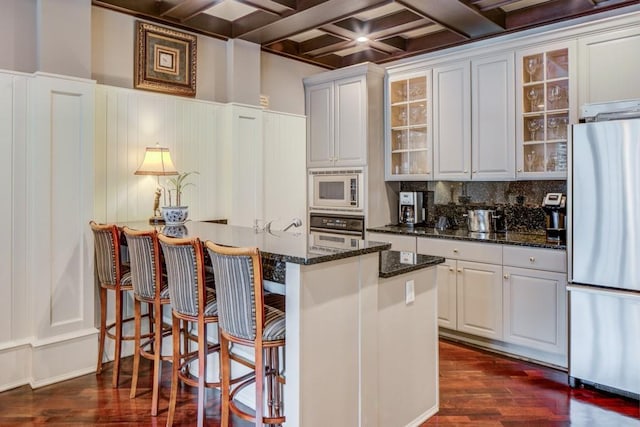 kitchen featuring glass insert cabinets, appliances with stainless steel finishes, dark wood finished floors, and beam ceiling