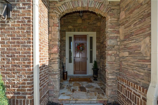 view of exterior entry featuring stone siding and brick siding